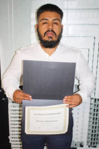 Kenny Alta, former Education is Forever student and current board member, proudly holds his Certificate of Scholarship, representing his journey from scholarship recipient to organizational leader and mentor.